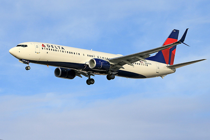 Delta Airlines plane mid-flight, clear sky in the background.