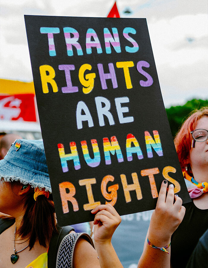 Person holding a sign saying "Trans rights are human rights" at a rally for transgender inclusion in sports.