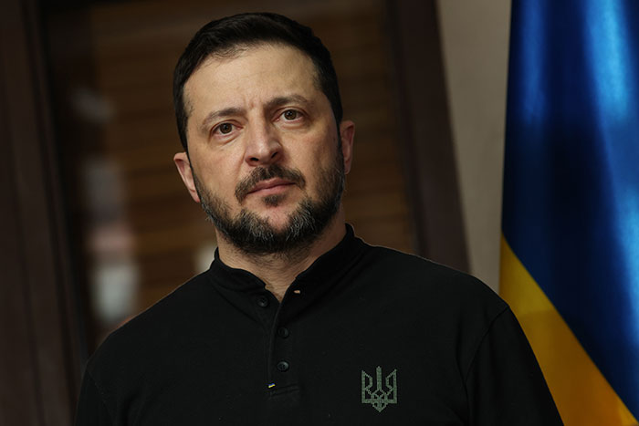 Man in a dark shirt in front of a flag, pertinent to NATO and Putin's Ukraine strikes topic.