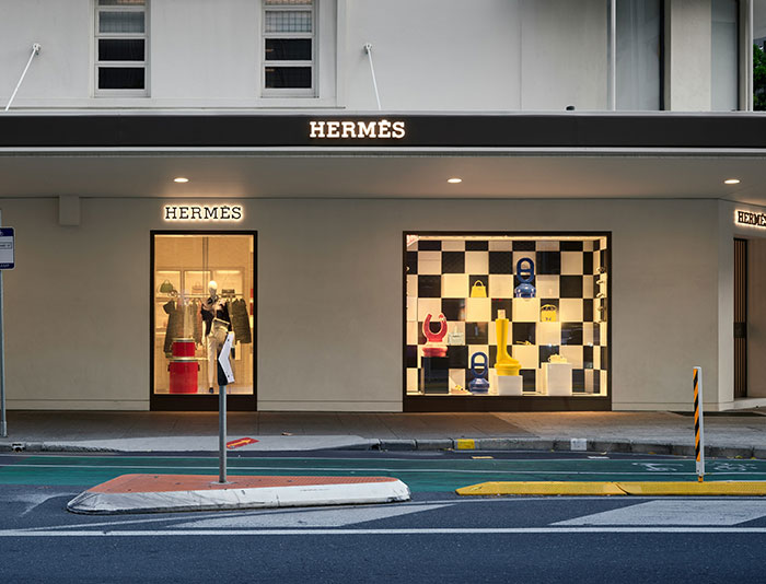 Hermès storefront with vibrant window display, showcasing direct-buy fashion choices, avoiding tariffs.