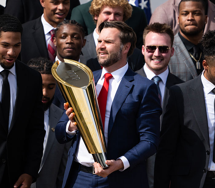 “Keep Them Down”: Trump Pulls Absurd Stunt To Look Taller Than Towering Ohio State Football Team
