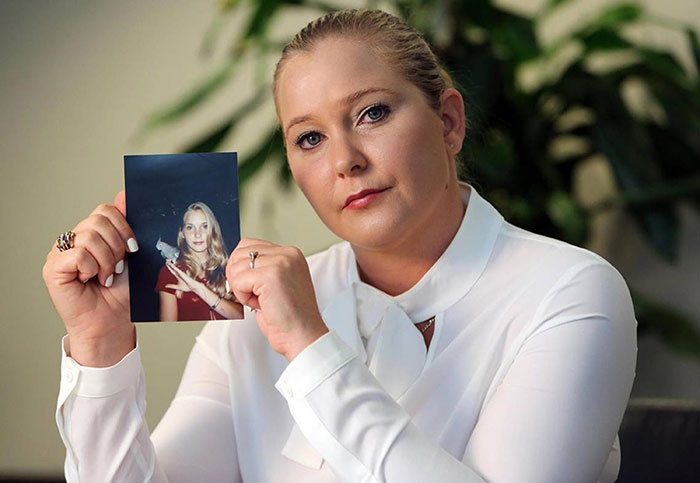 A woman holds a photo, linked to Virginia Giuffre and Epstein conspiracy discussion.