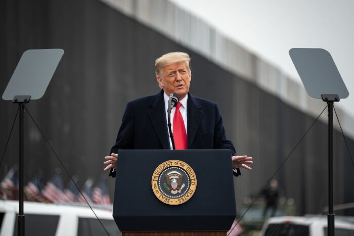 Former President Donald Trump speaking at a rally, with MAGA supporters and flags, linked to Pope Leo XIV agenda discussion.