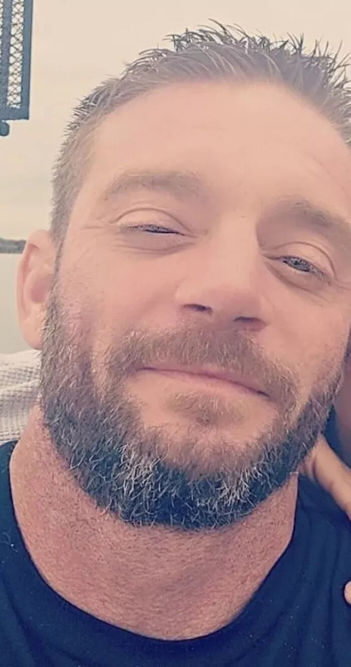 Close-up of a bearded man allegedly involved in a shooting case, facing new charges after his son’s tragic death.