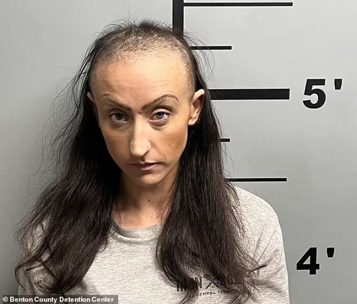 Mugshot of a woman with thinning hair standing against a height chart, related to alleged assault and starvation case.