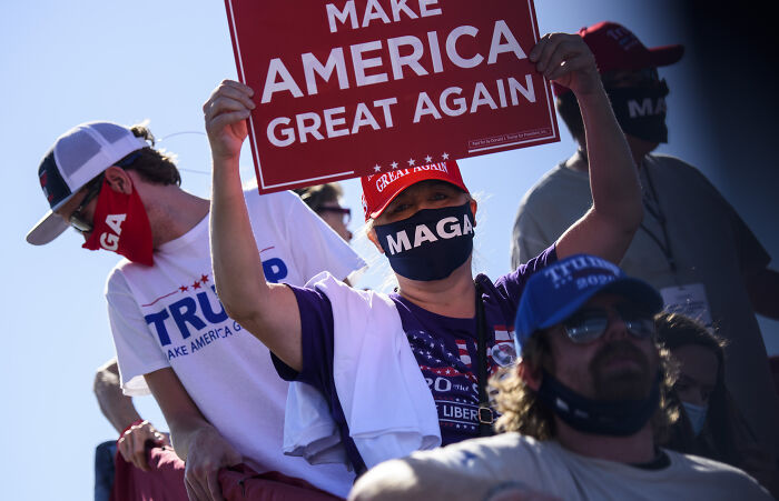 Supporters wearing MAGA gear and holding Make America Great Again signs at a political rally discussing Pope Leo XIV’s agenda.