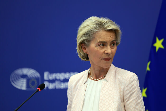 European official speaking at podium with EU flag in background, illustrating global trade and China winning the trade game.