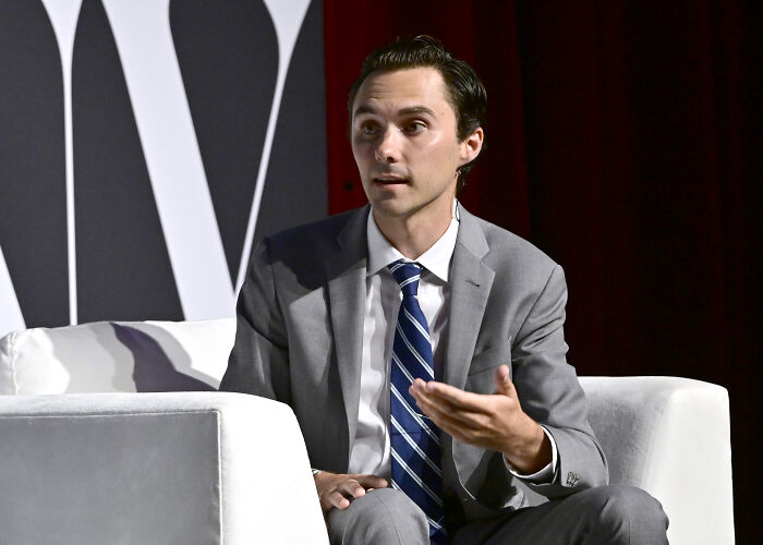 Man in gray suit and striped tie speaking during a formal event about DNC committee votes and David Hogg’s election.