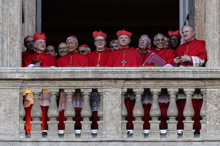 Group of cardinals in red robes on a balcony, highlighting clues to Pope Leo XIV’s agenda and MAGA reaction.
