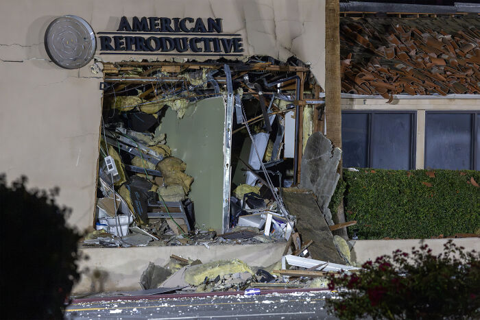 Damaged IVF clinic exterior with a large blown-out window showing extensive structural destruction.