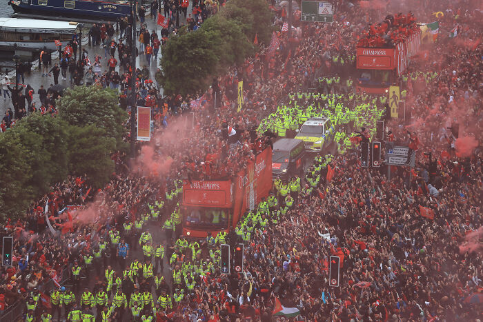 Liverpool FC parade with large crowds and heavy police presence amid fans vandalizing suspect’s car incident.