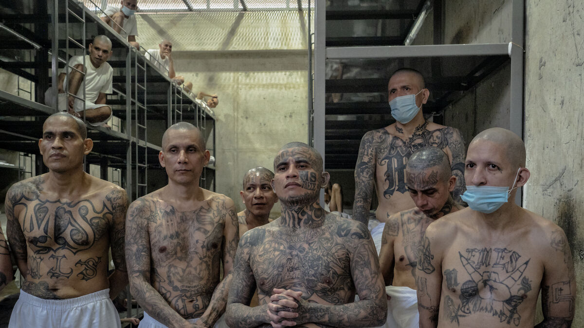 Group of tattooed migrants in a detention facility cell, highlighting conditions shown in drone footage with SOS message at Texas center.