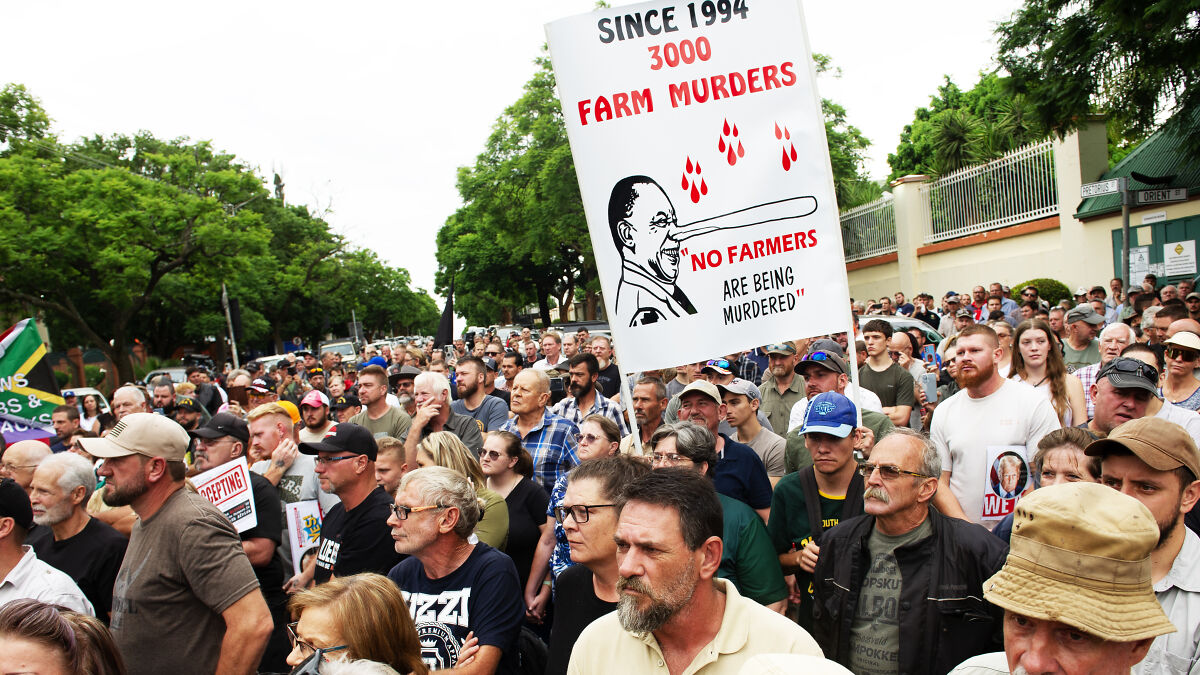 Crowd of white South Africans protesting farm murders, highlighting refugee status and departure for the U.S.