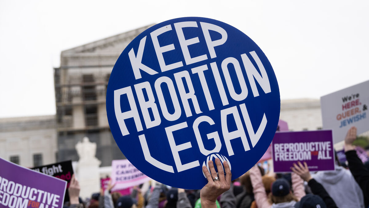Protesters holding signs supporting abortion rights and reproductive freedom outside a government building.