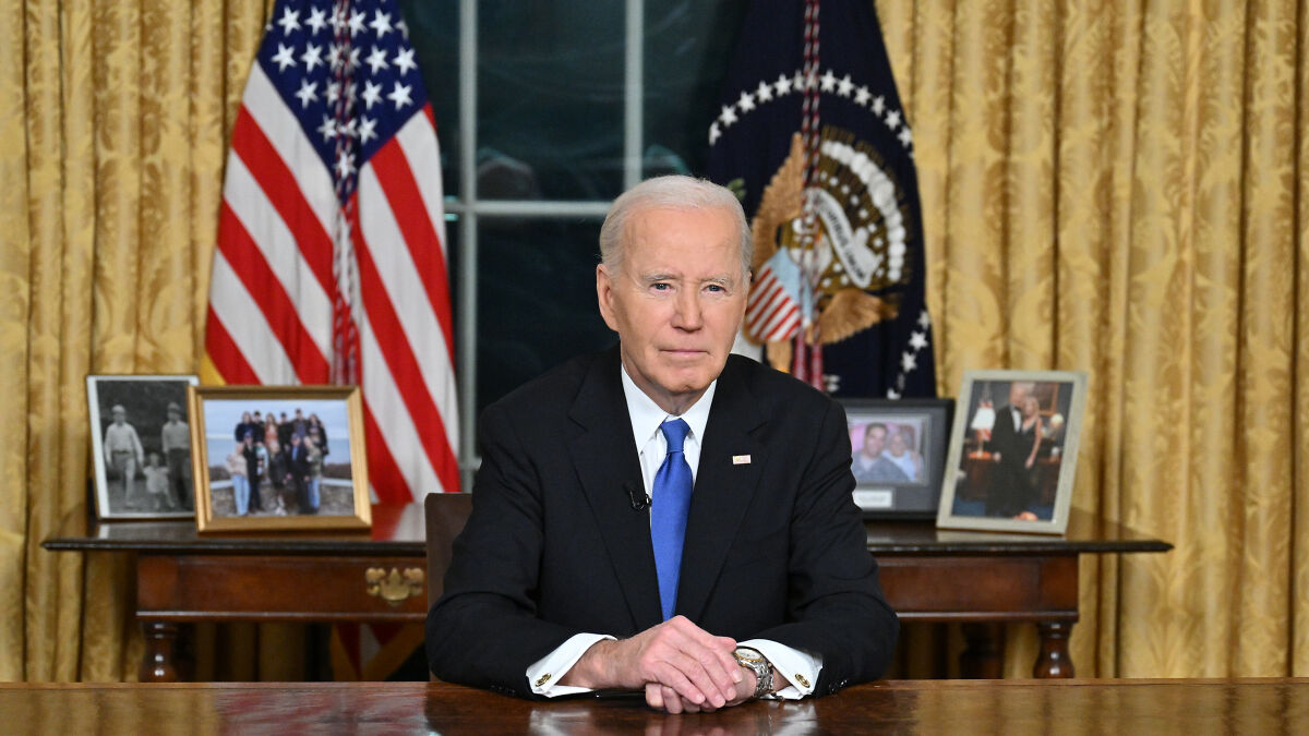 Joe Biden sitting at desk in Oval Office with American and presidential flags, addressing cancer diagnosis conspiracy theories.