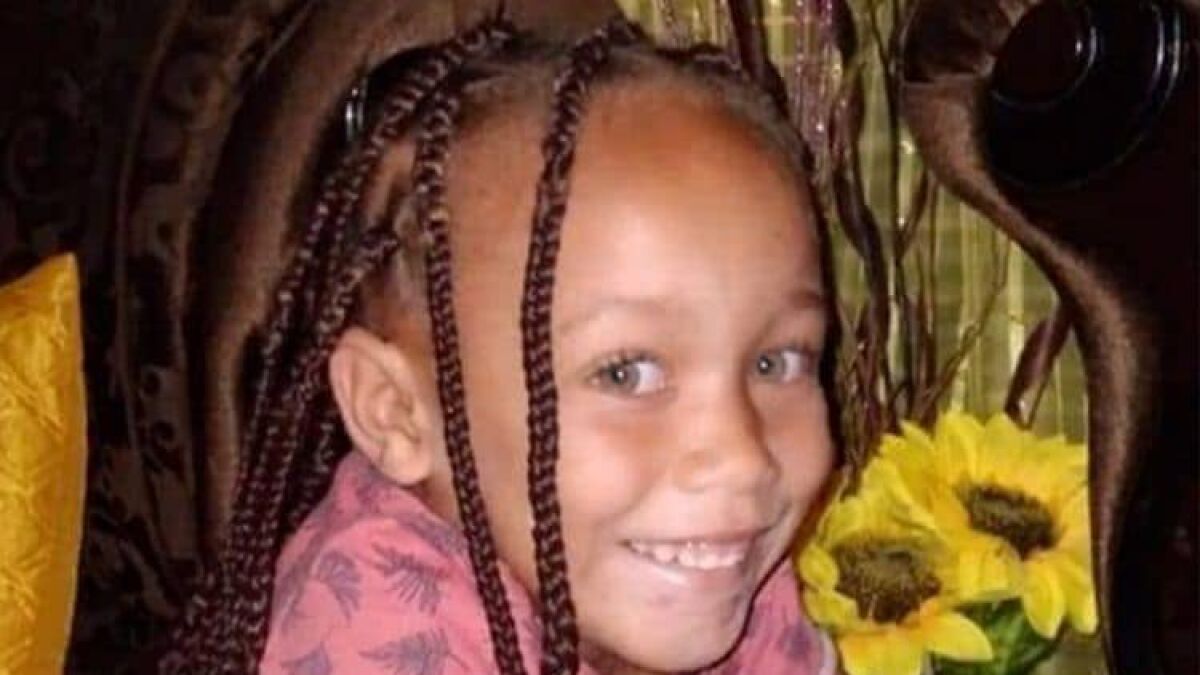 Young girl with braided hair smiling while holding sunflowers, related to mother jailed for selling daughter case.
