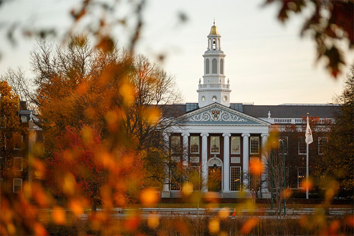 Harvard University campus in autumn with historic building and fall foliage, reflecting impact of Trump banning international students.