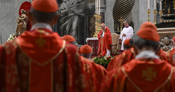 Catholic cardinals in red robes attending a ceremony inside a grand church in Rome.