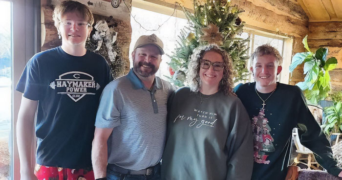 Family of four smiling indoors near Christmas tree, representing family found dead in suspected domestic homicide case.