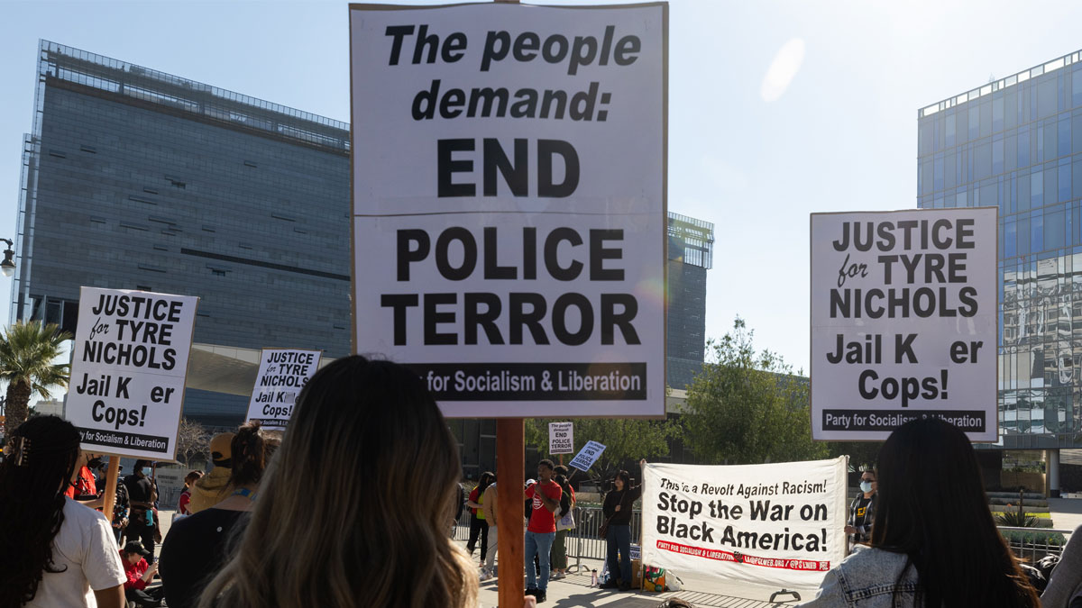 Protesters holding signs demanding justice for Tyre Nichols and an end to police terror during a public demonstration.