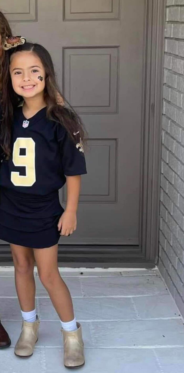 Young girl smiling in a sports jersey standing outside a house, related to Louisiana woman kills boyfriend’s daughter case.