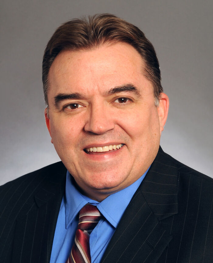 Headshot of a man in a blue shirt and striped tie representing the alleged shooter in lawmakers’ attack now in custody.