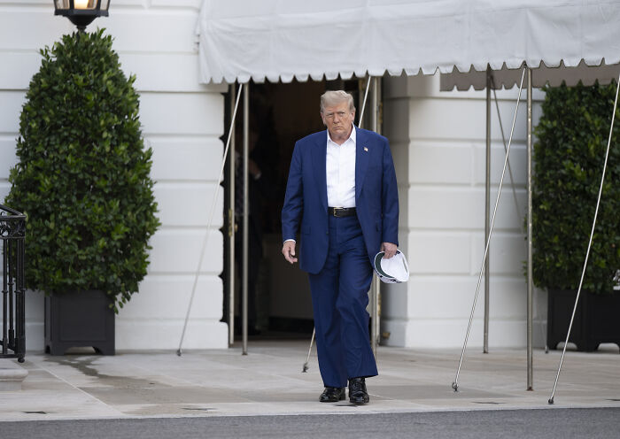 Former President Trump walking outside a building, related to early reports raising doubts on U.S. Iran strikes success.