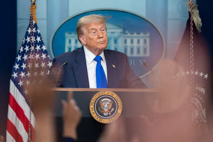 Former President Trump speaking at White House podium with US flags, illustrating GOP proposals and presidential fandom.