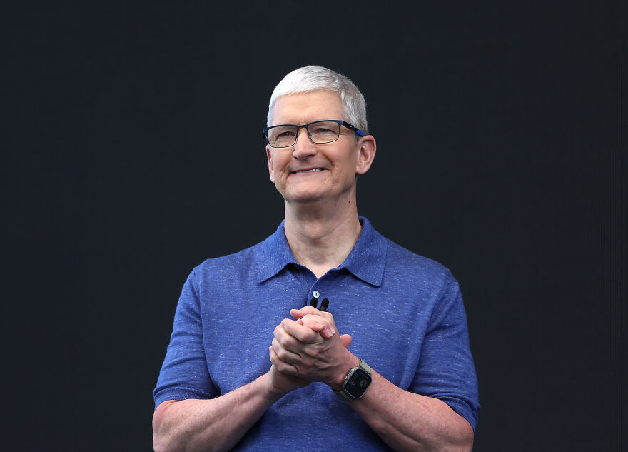 Man in glasses and blue shirt presenting technology, related to Trump Organization gold phones and Apple tariff threats.