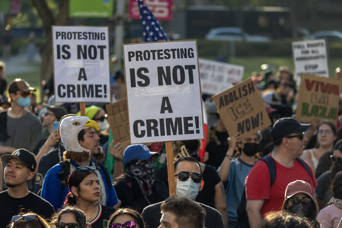 Protesters in a crowded demonstration holding signs against ICE amid Florida sheriff’s vow of deadly force on violent protestors.