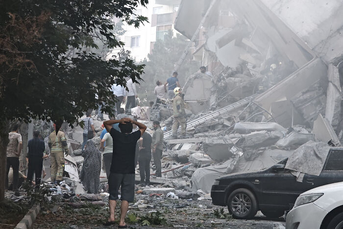 People search through rubble and smoke after Iran fires drones in overnight strikes, causing destruction and chaos.