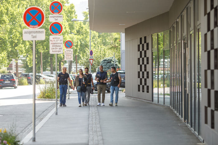 Group of plainclothes officers walking on sidewalk near no parking signs in Austrian city after shooter incident