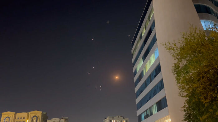 Missiles or drones seen over city buildings at night, related to Iran’s Supreme Leader warning to U.S. officials.