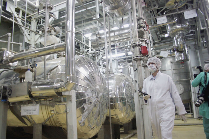 Technician in a nuclear facility inspecting equipment amid Iran vows of retaliation for U.S. nuclear strikes tensions.