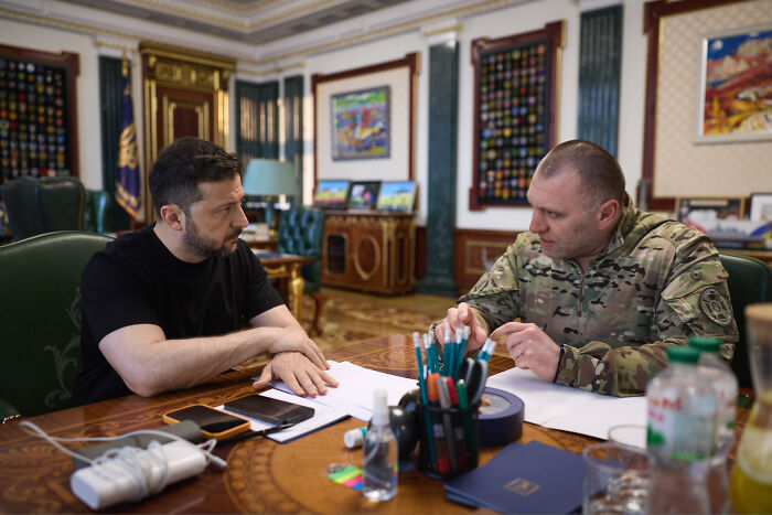 Ukrainian President Zelenskyy and military official in a meeting discussing strategy amid NATO strike warnings.