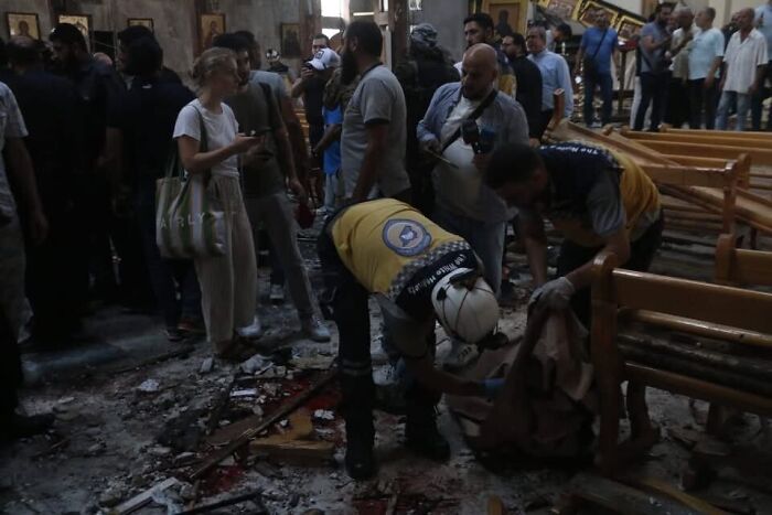 Rescue workers and civilians inside a damaged Greek Orthodox church after a suicide bombing in Syria causing casualties.
