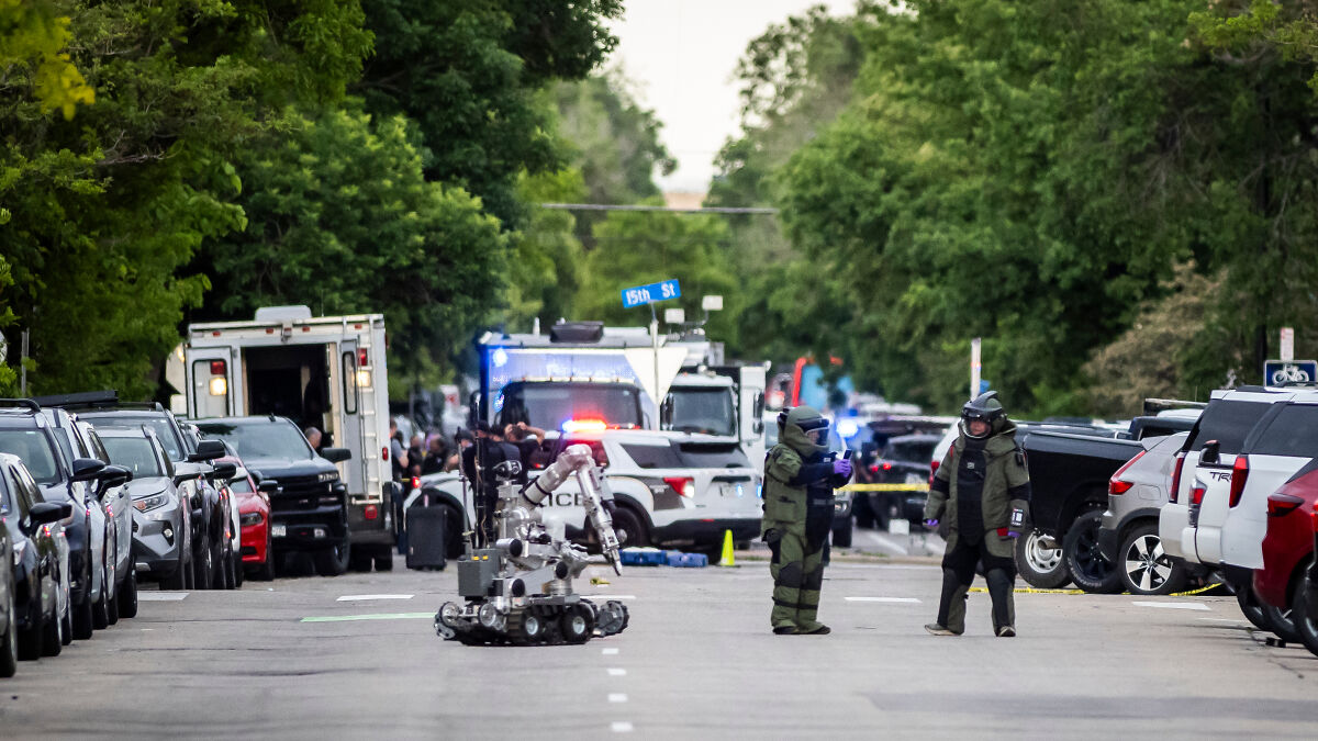 Bomb squad technicians and a bomb disposal robot on a street during FBI investigation of flamethrower attack in Colorado protest