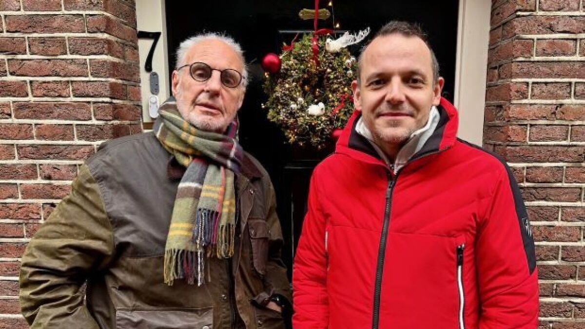 Two men standing outside a brick building with a wreath on the door, related to Sarco Pod advocate news.
