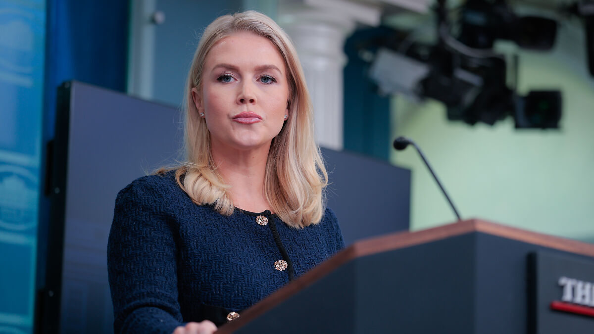 Karoline Leavitt at a podium, delivering a speech during a political event, with focused expression and blonde hair.