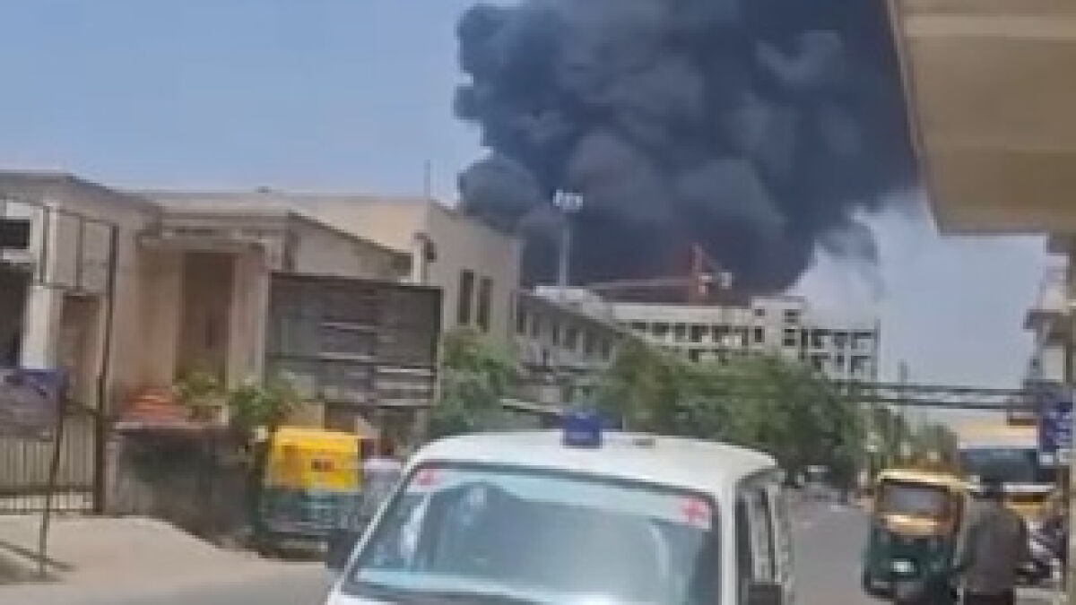 Thick black smoke rising over city buildings after Air India flight crash moments after take-off from airport.