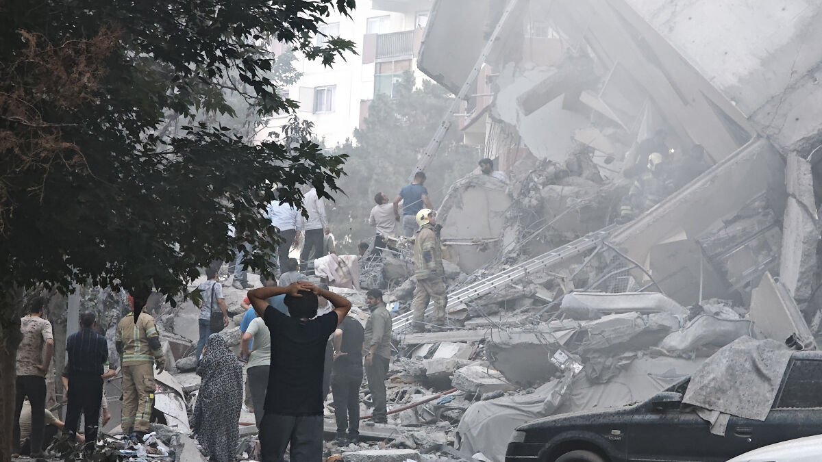 Crowd and rescue workers amid rubble of collapsed building after Iran fires drones in overnight strikes.