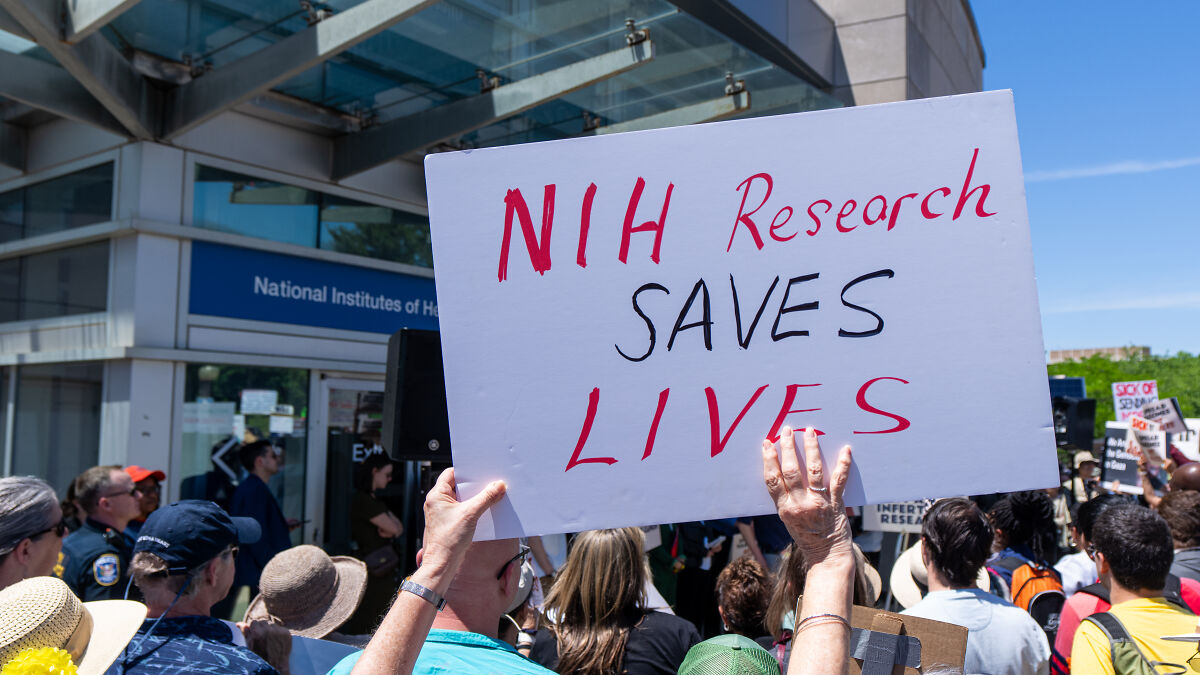 Protesters outside National Institutes of Health holding signs supporting NIH grants and research funding restoration.