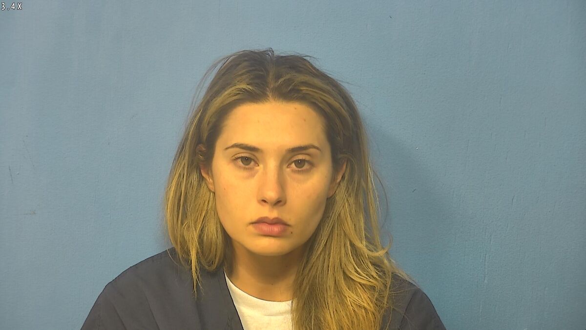 Mugshot of teacher accused of multiple sexual acts with pupil at school, looking directly at the camera against blue background.