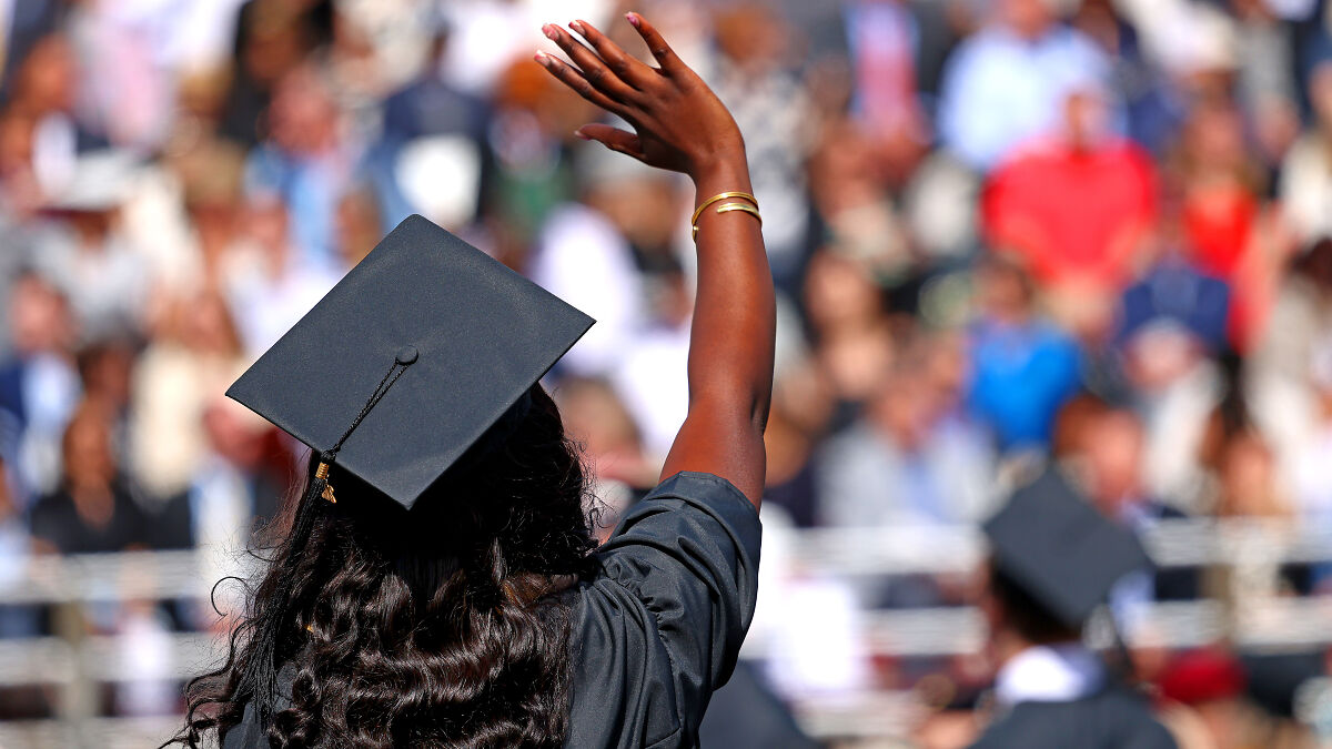 Graduate waving hand at commencement ceremony, representing foreign student visas and social media access requirements.