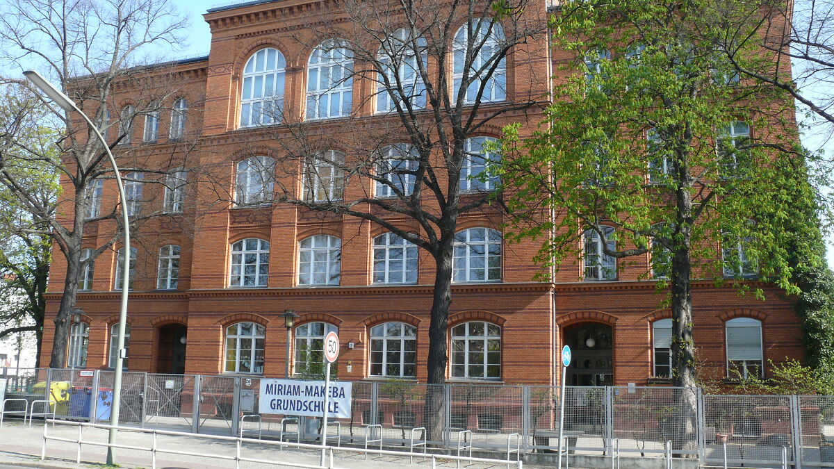 Berlin primary school exterior with trees and fencing after multiple children injured in tear gas incident.