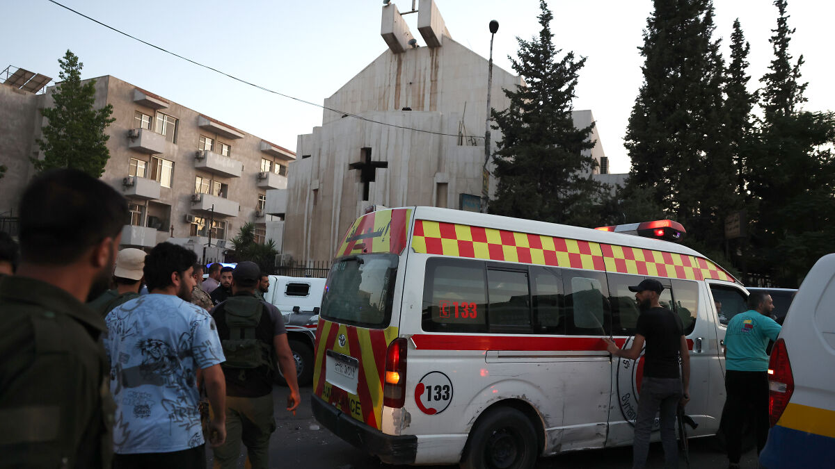 Emergency responders and armed men near a Greek Orthodox Church in Syria after suicide bombing causing casualties.