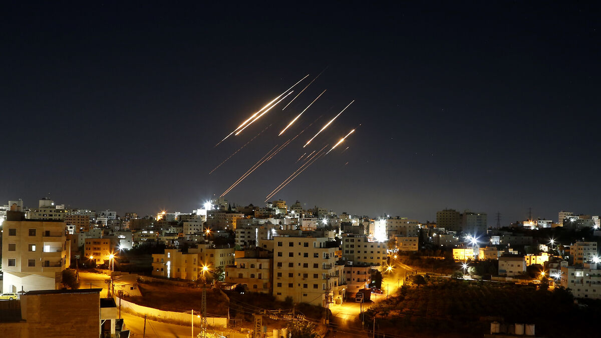 Night sky over city with bright streaks of light from possible missile strikes, highlighting U.S. Iran strikes impact.