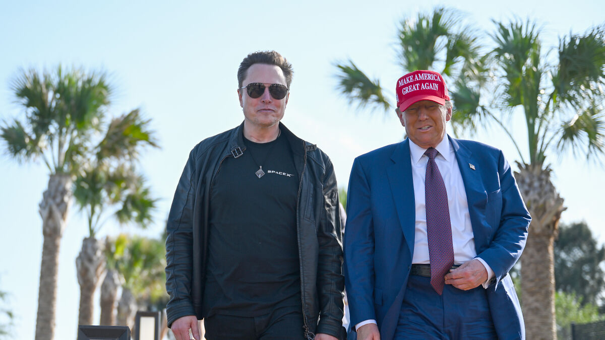 Elon Musk wearing sunglasses and Donald Trump in a red Make America Great Again hat walking outdoors with palm trees behind.