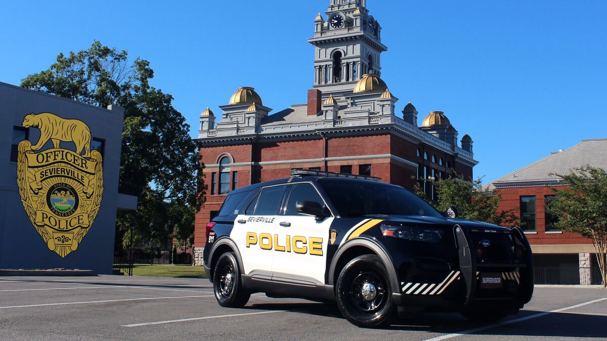 Sevierville police department vehicle parked outside historic courthouse under clear blue sky.