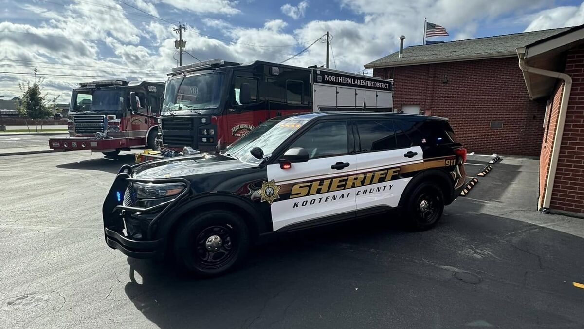 Kootenai County sheriff vehicle parked near Northern Lakes Fire District trucks at fire station in Idaho.